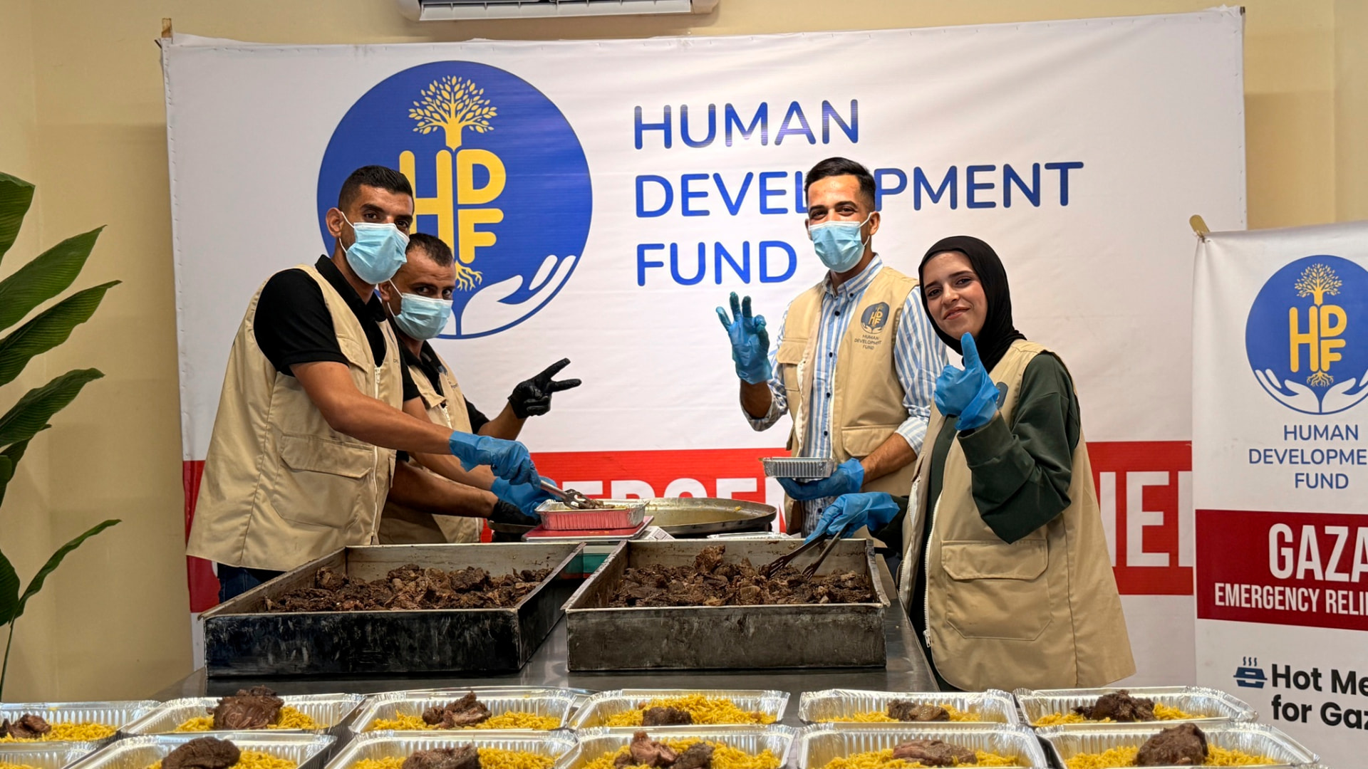 HDF kitchen team in Gaza preparing trays of hot meals under an HDF Gaza Emergency Relief banner